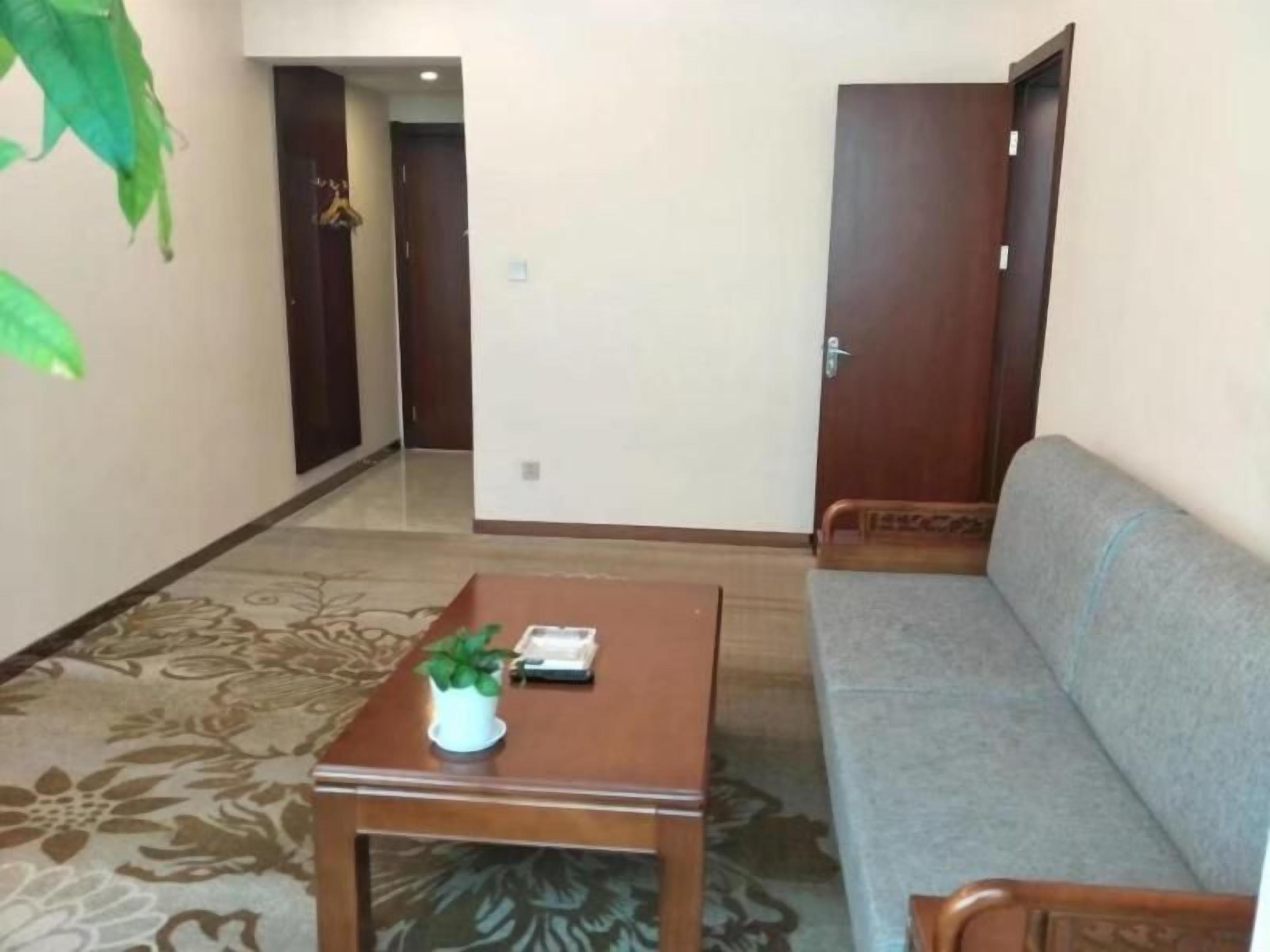 A room with a sofa, a wooden table with a plant, and a door.