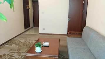 A room with a sofa, a wooden table with a plant, and a door.