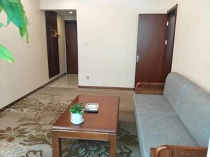 A room with a sofa, a wooden table with a plant, and a door.