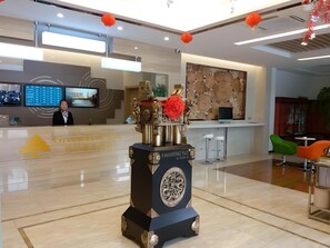 Zona de recepción con diseño moderno, que incluye un mostrador de recepción, pantallas digitales y un elemento decorativo central.