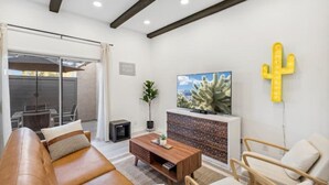 A modern living room with a leather sofa, wooden coffee table, and a cactus wall decoration. - Desert Gem-Walk To Spring Training,ASU,Tempe Lake! (Tempe)