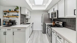 A modern kitchen with white cabinets, a skylight, a microwave, and a stove. - Desert Gem-Walk To Spring Training,ASU,Tempe Lake! (Tempe)