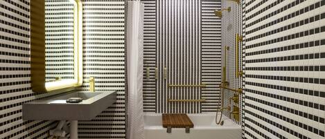 Ein Badezimmer mit einem weißen Waschbecken, einem Spiegel, einer Dusche mit gebogener Glastür und einer Badewanne.