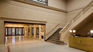 A spacious lobby with a grand staircase, a reception desk, and a large open area with a high ceiling. - Renaissance New York Harlem Hotel (New York)