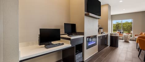 A modern kitchen with built-in appliances, a flat-screen TV, and a seating area with orange chairs.