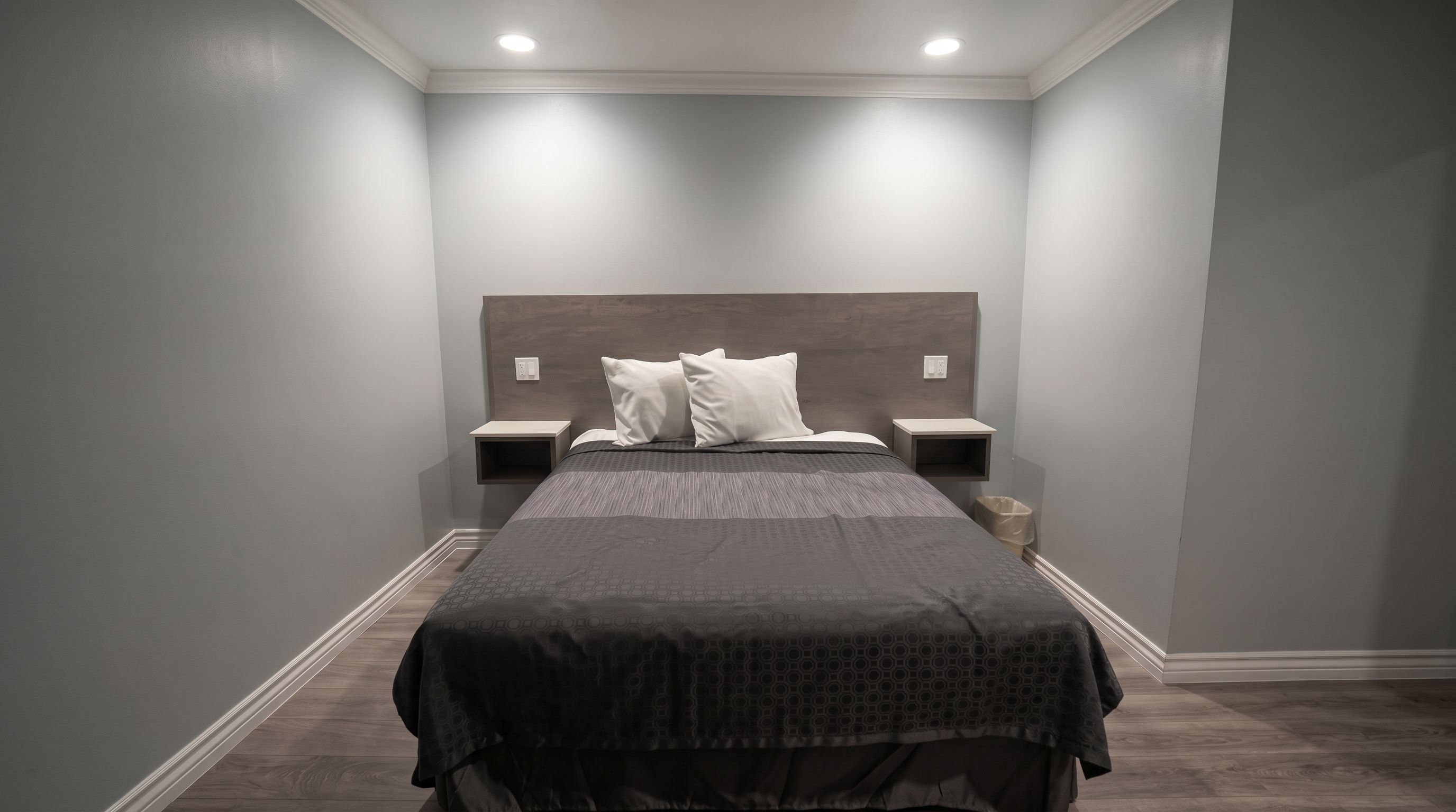 Un dormitorio con cama, dos mesitas de noche y una lámpara de pared.