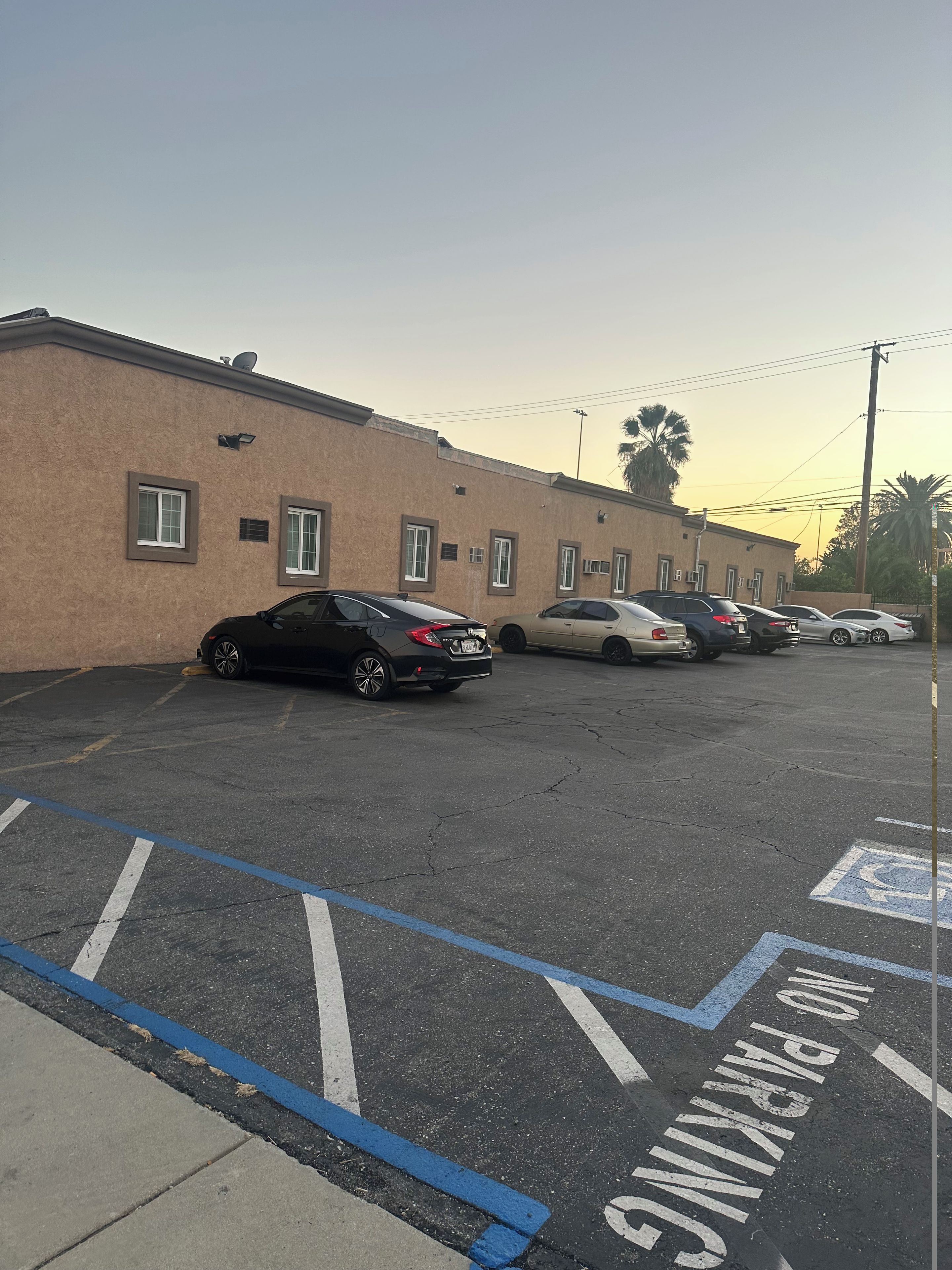 A parking lot with multiple cars parked in front of a building with a beige facade.