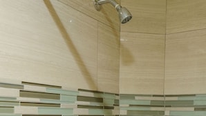 A shower with a glass door, a metal handle, and a showerhead.