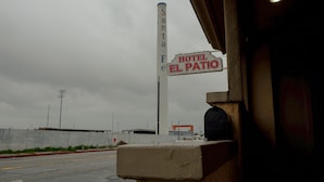 A sign for 'HOTEL EL PAJITO' with a tall chimney in the background.
