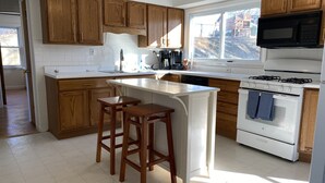 A kitchen with wooden cabinets, a white countertop, a stove, and a window. - Cozy 2 bedroom + sleeping are close to Grant's Farm trail & 15 min. to downtown (St. Louis)