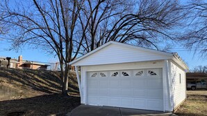 A white garage with a sloped roof and multiple garage doors. - Cozy 2 bedroom + sleeping are close to Grant's Farm trail & 15 min. to downtown (St. Louis)