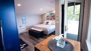 A bedroom with a bed, bedside table, and a window. - Luxury Waterfront Tiny House (Harpswell)