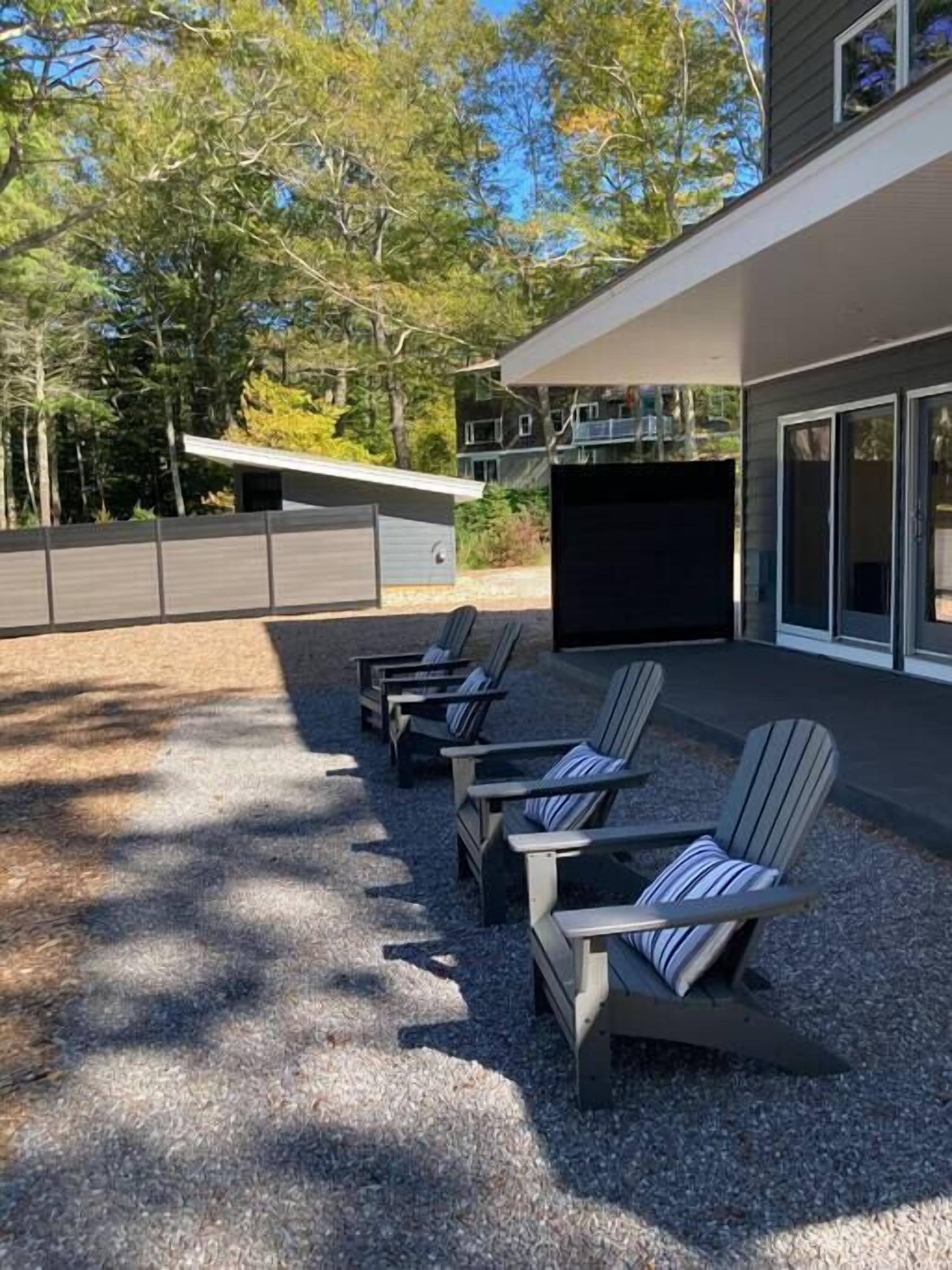 Un espace extérieur moderne aménagé avec des chaises Adirondack et un barbecue.