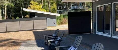 Un espace extérieur moderne aménagé avec des chaises Adirondack et un barbecue.