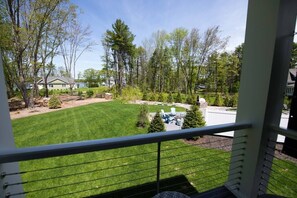 A balcony with a view of a well-maintained lawn, trees, and a distant house. - Modern Cottage with Ocean Access & Wildlife (Harpswell)