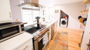 A modern kitchen with stainless steel appliances, a built-in oven, and a washing machine. - Modern Cottage with Ocean Access & Wildlife (Harpswell)