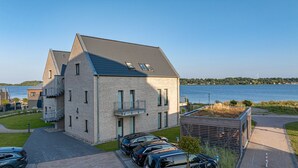 Ein modernes, zweistöckiges Gebäude mit geneigtem Dach, großen Fenstern und Seeblick.