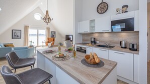 Eine moderne Küche mit weißen Schränken, einer Holz Arbeitsplatte und einem eingebauten Bosch-Mikrowellenherd.
