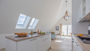 Eine moderne Küche mit einer großen Kochinsel, Oberlichtern und einer Kandelaberleuchte.