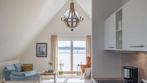 Ein modernes Wohnzimmer mit Sofa, Couchtisch und Blick auf das Wasser.