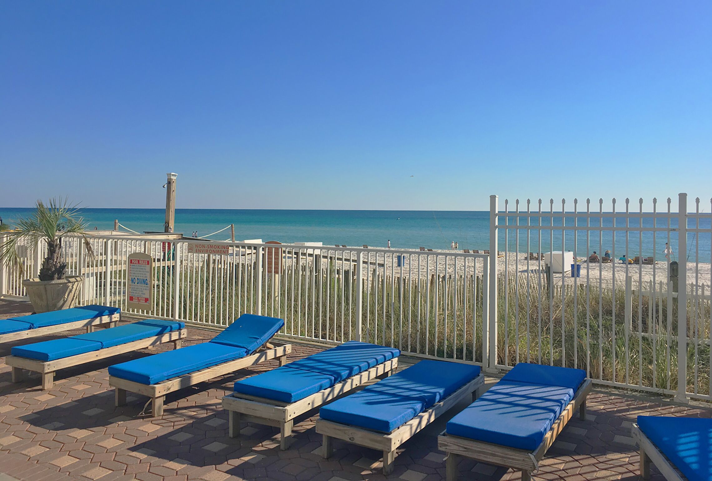 A beachside lounge area with wooden sunbeds and a view of the ocean.