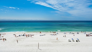 Uma praia com areia branca, águas azul-claras e uma rede de voleibol.