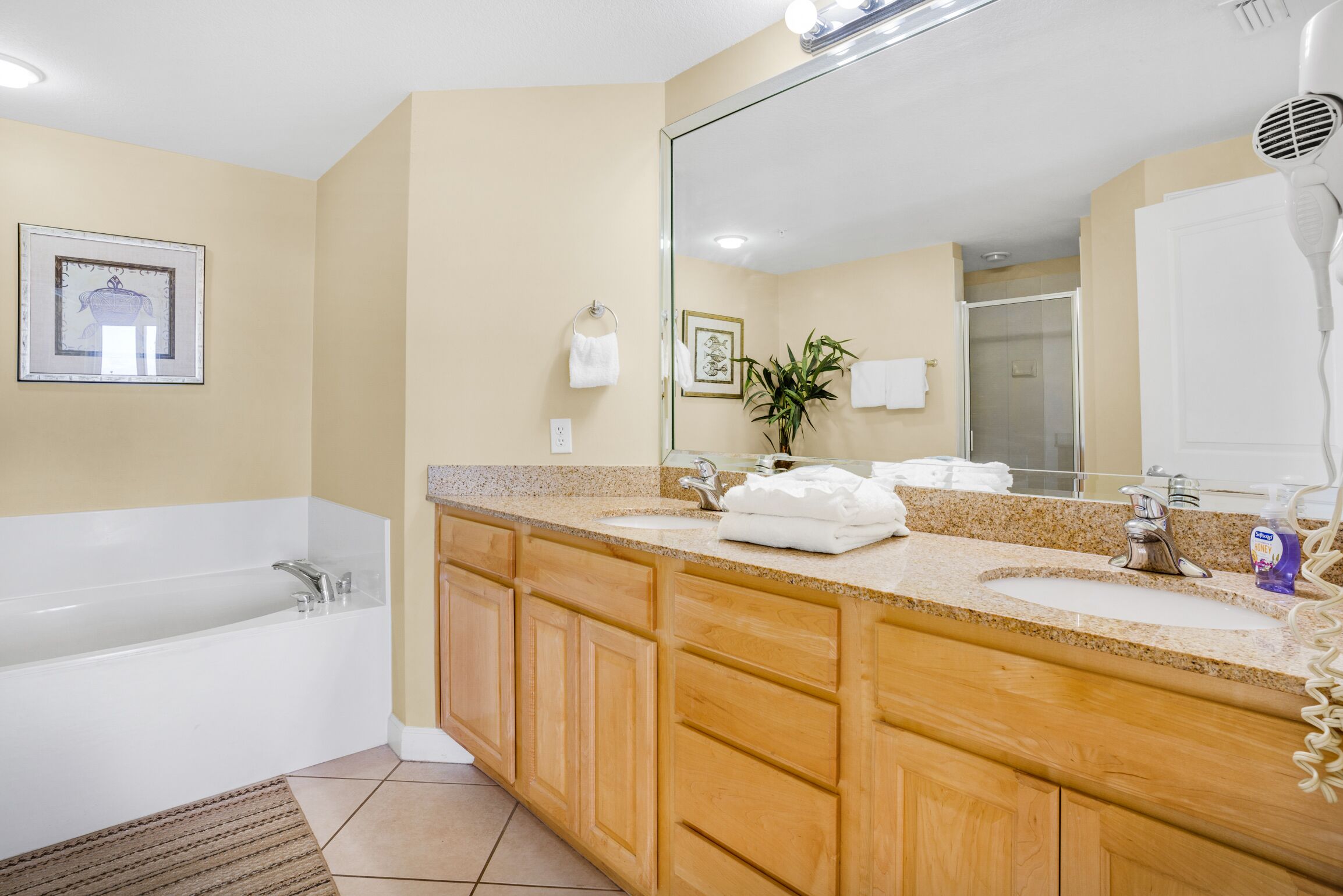 Une salle de bain moderne avec une baignoire, un meuble-lavabo en bois, deux vasques et un grand miroir.
