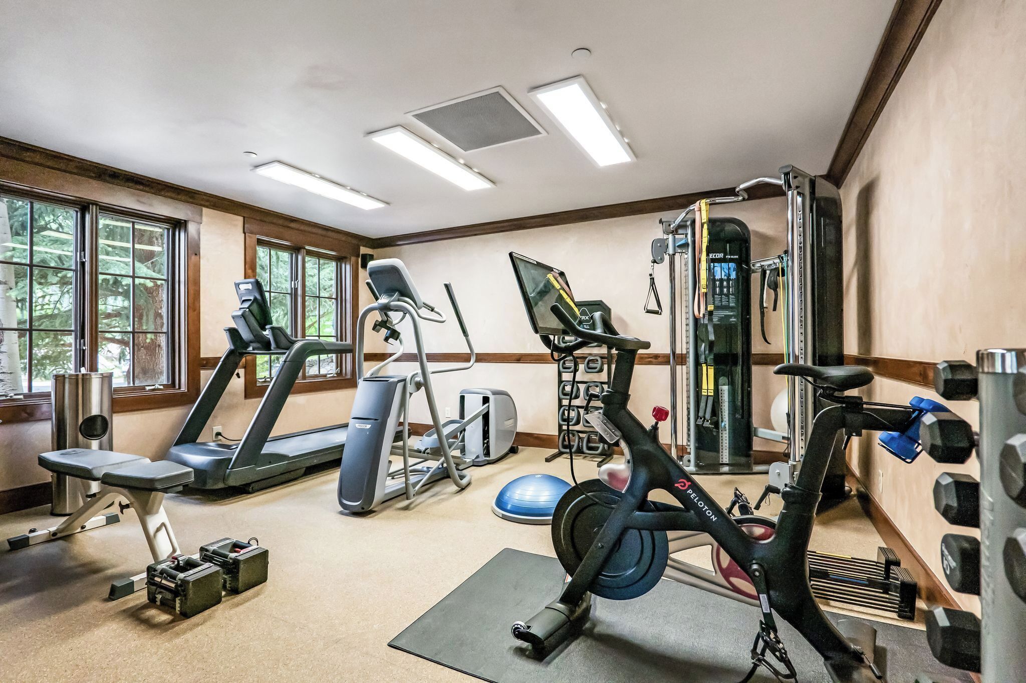 Une salle de sport équipée de tapis de course, d’un vélo elliptique, d’un vélo d’appartement et de poids libres.