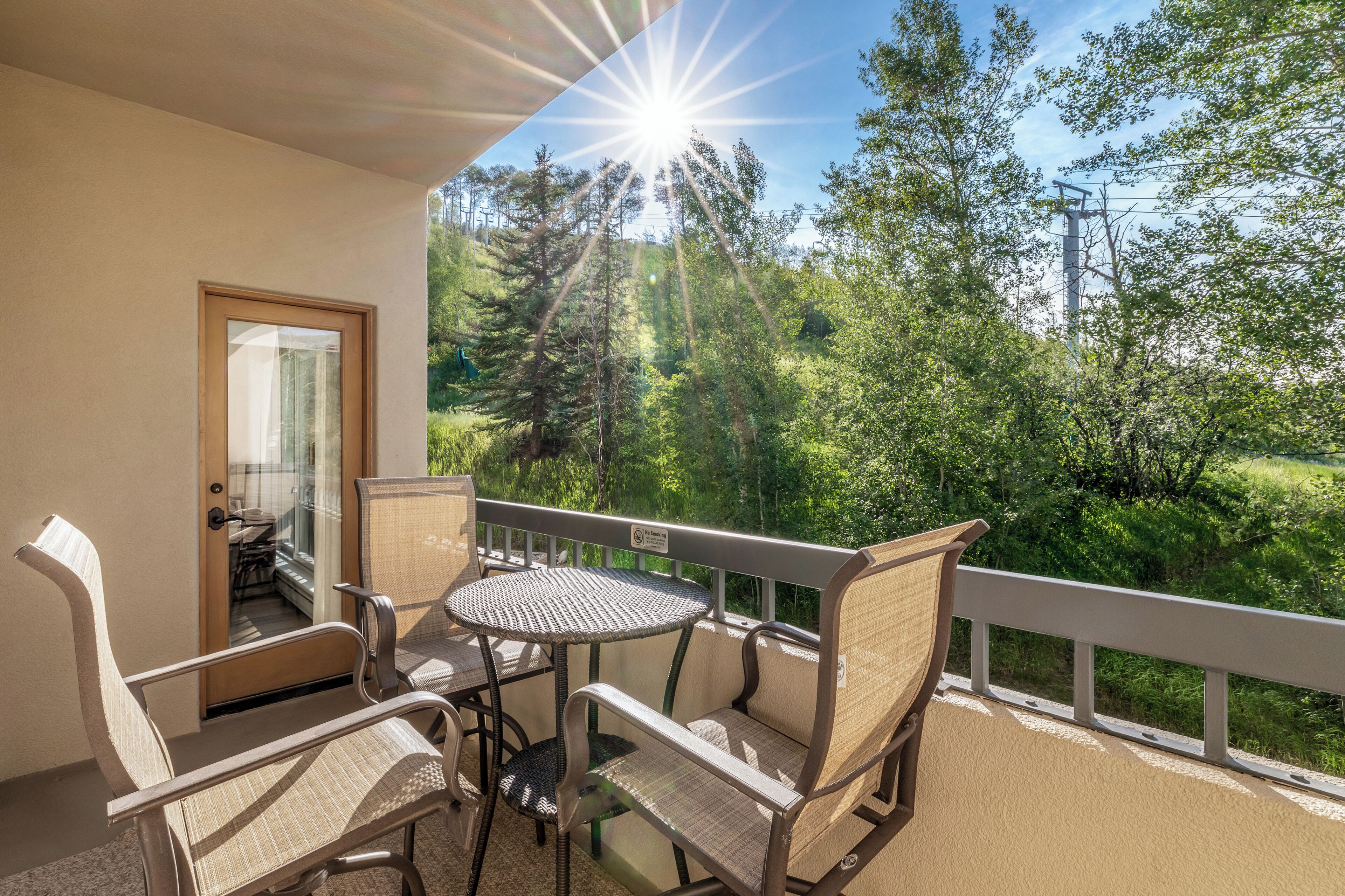 A balcony with wicker furniture and a view of a forest.