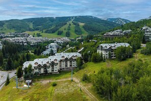 A resort with multiple buildings, a ski lift, and a mountainous backdrop.