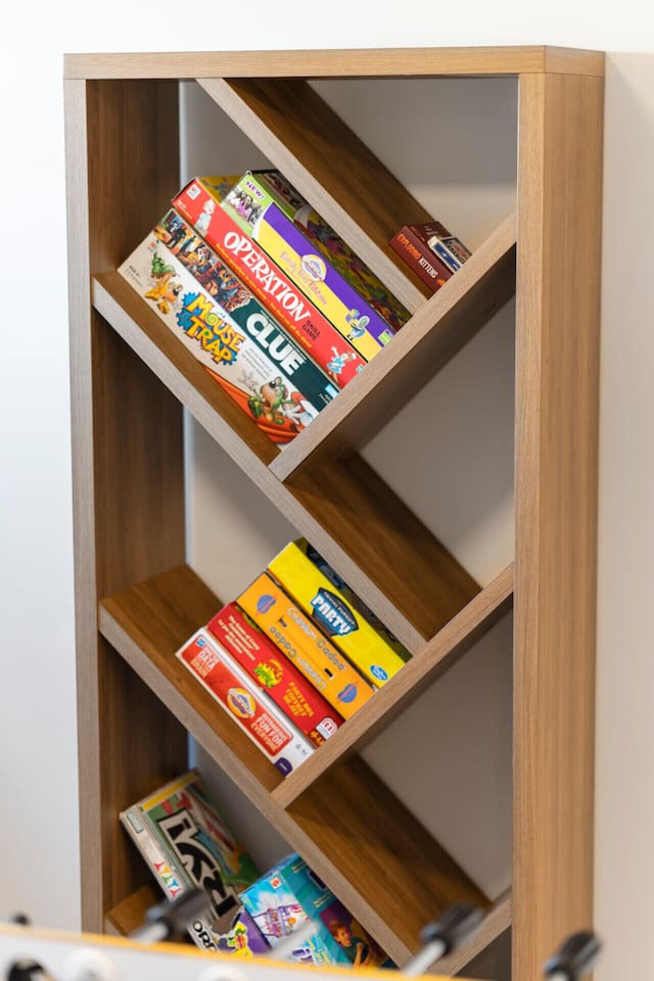 Een houten boekenkast met verschillende gezelschapsspellen en puzzels.