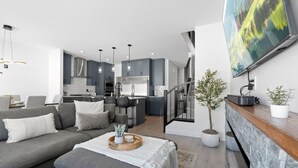 Una sala de estar moderna con un sofá gris, una mesa de centro con objetos decorativos y un televisor montado en la pared.