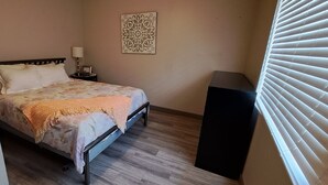 Ein Schlafzimmer mit Bett, Nachttisch, Lampe und einer Wanddekoration.