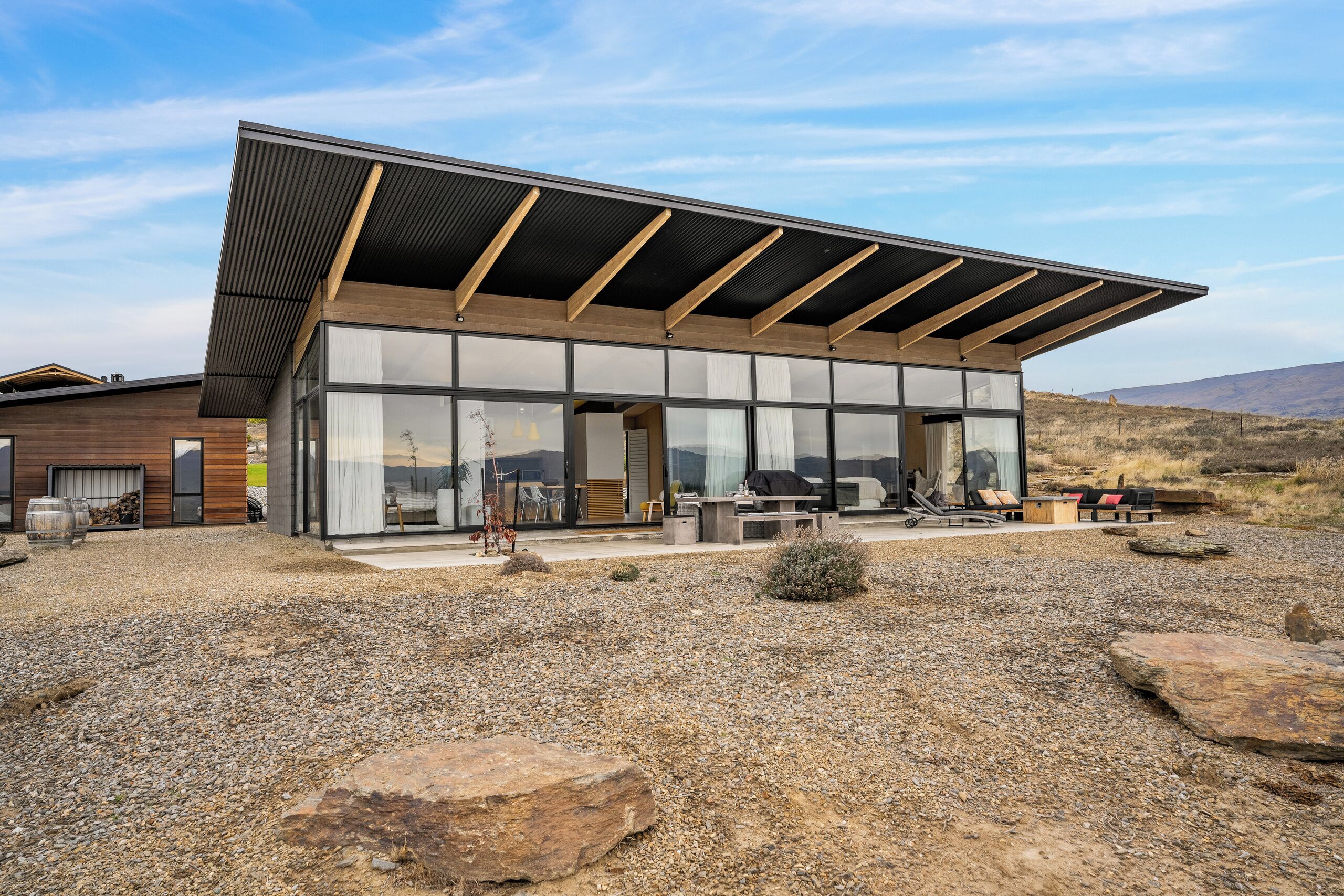 A modern building with large glass windows, a flat roof, and a gravel ground.