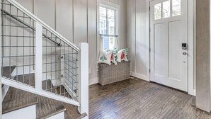 Un escalier avec une rampe en métal, un plancher en bois, une porte blanche et un luminaire suspendu.