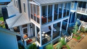Une maison à plusieurs étages dotée d’un balcon, d’un porche et d’un espace extérieur aménagé et abrité.