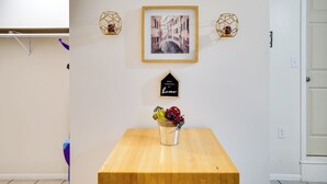 A room with a wooden table, a framed picture of a bridge, two wall-mounted lights, and a small sign on the wall. - Lakeland Vacation Rental: 38 Mi to Disney! (Lakeland)