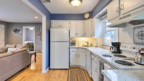 A compact kitchen with white cabinets, a refrigerator, a stove, and a coffee maker. - Charming Rocky Point Home ~ 1 Mi to Beach! (Rocky Point)
