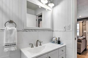 Een moderne badkamer met een witte wastafel, twee kraanwerk, een grote spiegel en een handdoekhouder.