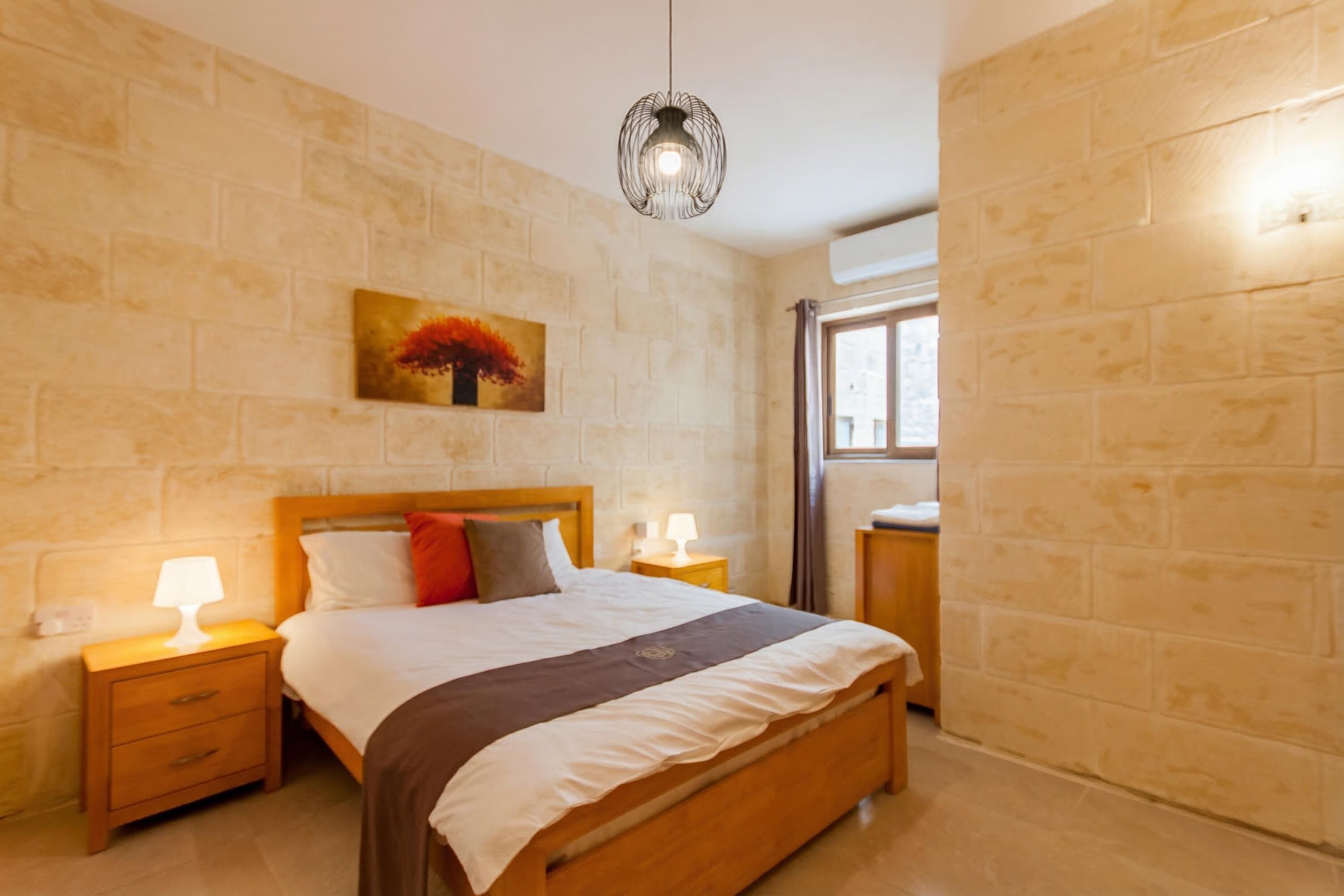 A bedroom with a wooden bed, bedside lamps, a painting on the wall, and a window with curtains.