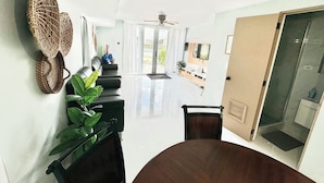 A modern living room with a dining area, a TV, and a glass door leading to a balcony. - Eco-Luxury Villa with Pool, Beach Access, and 24 hour I uninterrupted power (Dorado)
