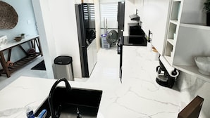 A modern kitchen with white marble countertops, a built-in dishwasher, and a coffee machine. - Eco-Luxury Villa with Pool, Beach Access, and 24 hour I uninterrupted power (Dorado)
