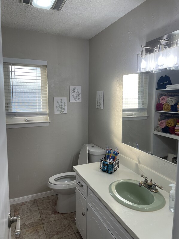 Un baño con inodoro, lavamanos y ventana con persianas.