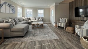 A living room with a sectional sofa, a coffee table, a TV, and a fireplace.