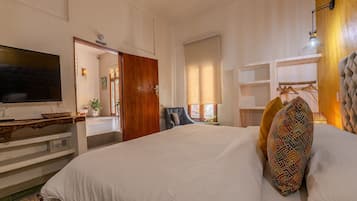 A hotel room with a large bed, a TV, a wooden door, and a view of the outside.