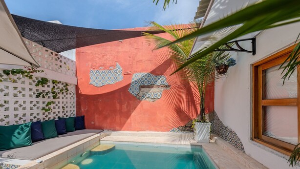 A small outdoor pool with a tiled deck, a seating area with cushions, and a decorative wall with a geometric pattern. - Casa Moraira (Cartagena)