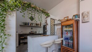 A kitchen with a bar area, a refrigerator with beverages, and a hanging plant. - Casa Moraira (Cartagena)