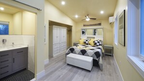 Une chambre à coucher avec un lit, des tables de chevet, un ventilateur de plafond et une fenêtre.