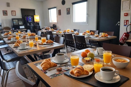 A breakfast buffet with tables set with croissants, orange juice, and coffee.