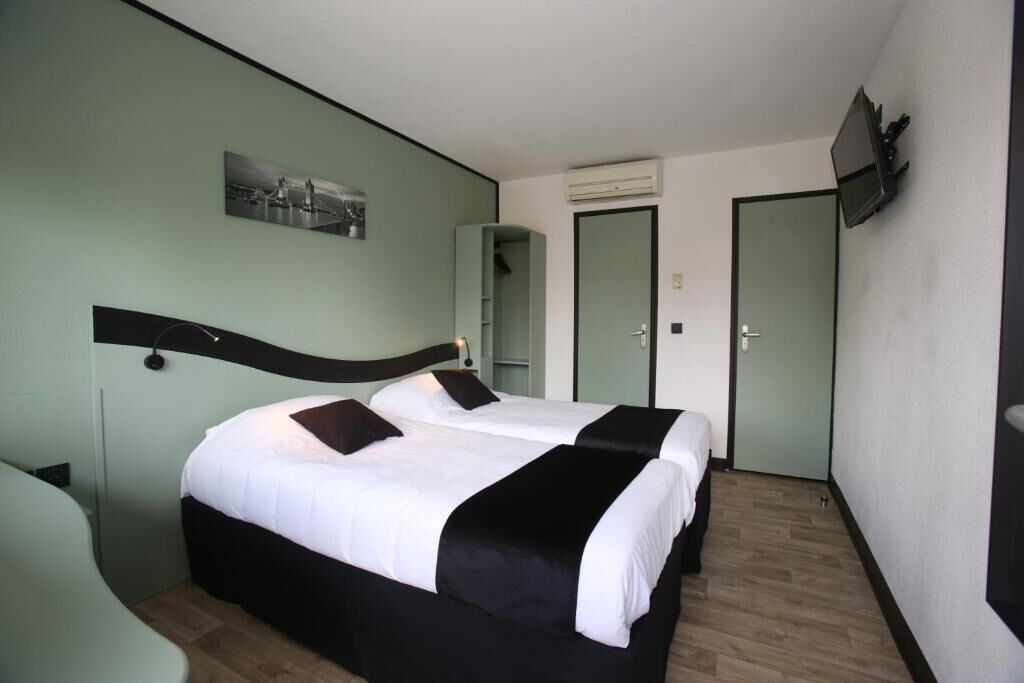 Habitación de hotel con dos camas, una televisión de pantalla plana, un cuadro en la pared y un espejo.